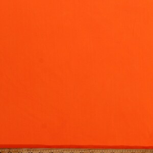 May include: A bright orange fabric swatch with a wooden ruler measuring 26 inches.