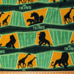 May include: Green and yellow fabric with a repeating pattern of silhouettes of animals from The Lion King. The animals include lions, giraffes, and a warthog. The text "The Lion King" is repeated throughout the fabric.