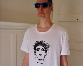 May include: A white t-shirt with a black and white illustration of a person's face on the front. The person is wearing sunglasses.