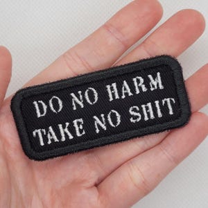 May include: Black embroidered patch with white text that reads "Do No Harm Take No Shit".