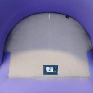 May include: Purple fabric chair with a white fabric seat. The seat has a label that reads "Fairfield, The Standard of Quality".