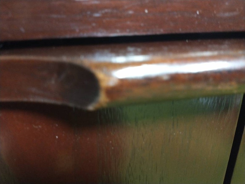Pu&ograve; includere: Primo piano di una porta di armadio in legno marrone scuro con una maniglia in legno marrone scuro liscia.