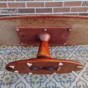 May include: A vintage, oval-shaped wooden table with a dark brown finish. The table has a pedestal base and a light-colored underside. The table is approximately 48 inches long and 30 inches wide.