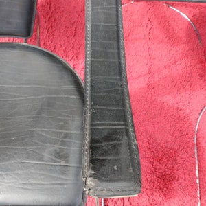 May include: Close-up of a black leather chair with chrome legs. The chair has a padded seat and back, and the leather is stitched with a diamond pattern.
