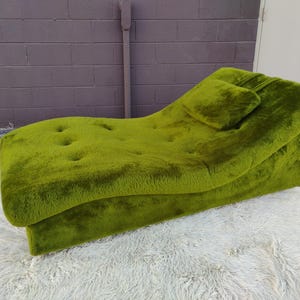 May include: A lime green, mid-century modern chaise lounge with a tufted seat and attached pillow. The plush, textured fabric covers the entire piece. The chaise is set on a white, shaggy rug.
