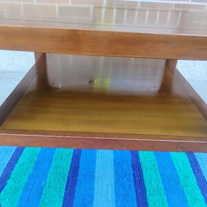 May include: A wooden coffee table with a lower shelf. The table has a simple, mid-century modern design.