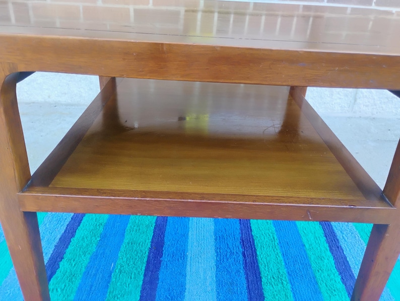 May include: A wooden coffee table with a lower shelf. The table has a simple, mid-century modern design.