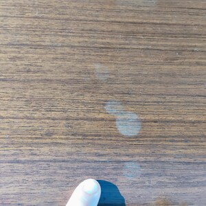 May include: Close-up of a light brown wooden surface with several light-colored watermarks.