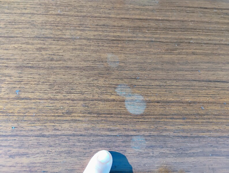 May include: Close-up of a light brown wooden surface with several light-colored watermarks.