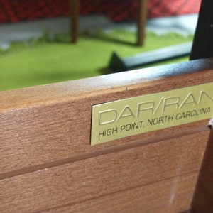 Pu&ograve; includere: Primo piano di un cassetto in legno con un'etichetta in metallo dorato che recita "DAR/RAN HIGH POINT, NORTH CAROLINA".