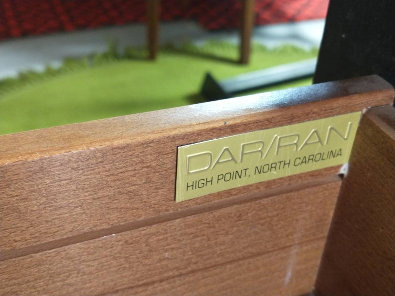 Pu&ograve; includere: Primo piano di un cassetto in legno con un'etichetta in metallo dorato che recita "DAR/RAN HIGH POINT, NORTH CAROLINA".
