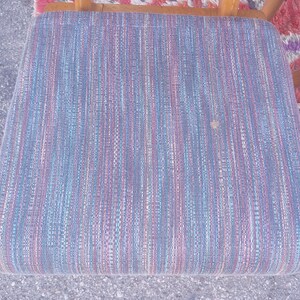 May include: A blue, pink, and white striped chair seat with a woven fabric texture.