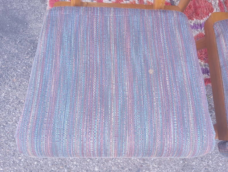 May include: A blue, pink, and white striped chair seat with a woven fabric texture.