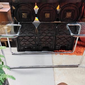 Peut inclure: Une table basse en verre transparent avec un plateau rectangulaire et un cadre en m&eacute;tal chrom&eacute;. La table a un design moderne et est soutenue par des pieds incurv&eacute;s. La table mesure environ 122 cm de long et 61 cm de large.