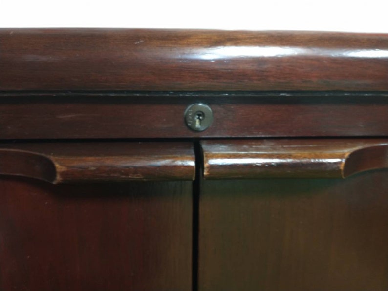 Pu&ograve; includere: Un armadio in legno scuro con due ante e un buco della serratura. L'armadio ha un design semplice con una finitura liscia.
