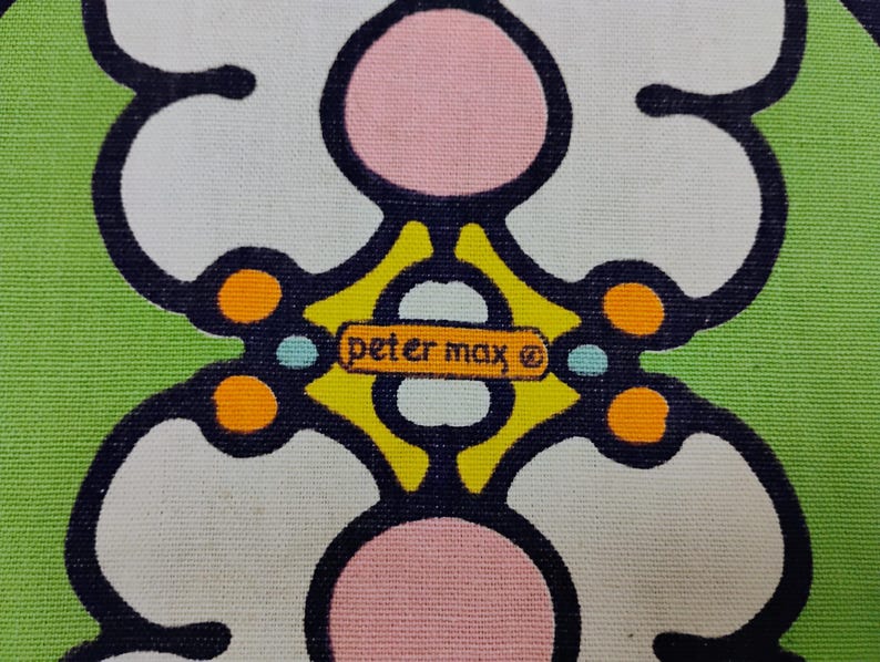 May include: Close-up of a fabric with a repeating floral pattern in white, pink, and black on a green background. The design includes the text "peter max" in a small rectangular box.