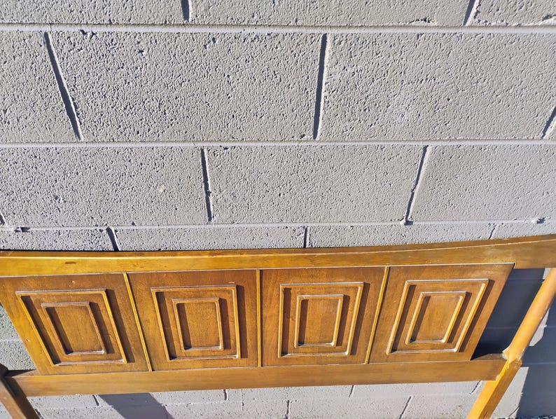 May include: A wooden headboard with a geometric design. The headboard is made of light brown wood and has a rectangular shape. The headboard is in good condition and has no visible damage.