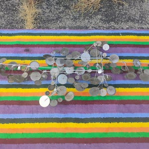 May include: A wall sculpture featuring a horizontal metal frame with numerous thin wire stems extending outward. Attached to these stems are various circular metal discs in shades of silver, gray, and muted brown, creating a layered, branching effect.