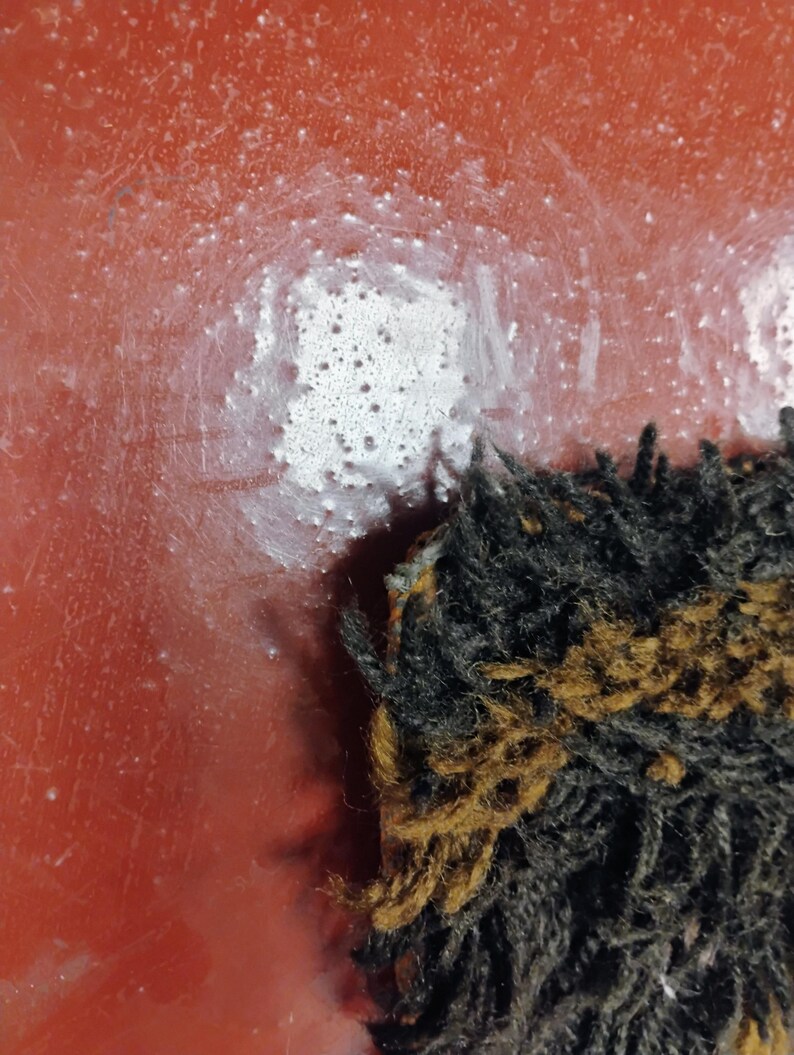 May include: Close-up of a red surface with white paint splatters. A black and brown fuzzy object is in the bottom right corner of the image.
