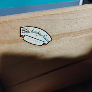 May include: Close-up of a light-colored wooden drawer with a label. The label reads "Winchendon Modern" in black script, with a red and white border, and the number "NO. 1509".