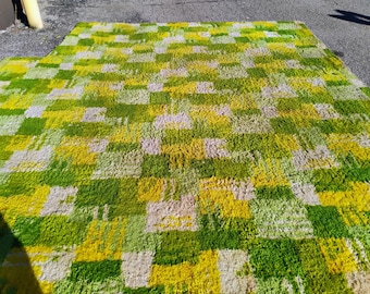 Könnte beinhalten: Ein rechteckiger Teppich mit hochflorigem, zotteligem Flor und einem geometrischen Blockmuster. Das Design besteht aus abwechselnden Quadraten und Rechtecken in den Farben leuchtendes Gelb, Limettengrün, Waldgrün und Off-White.