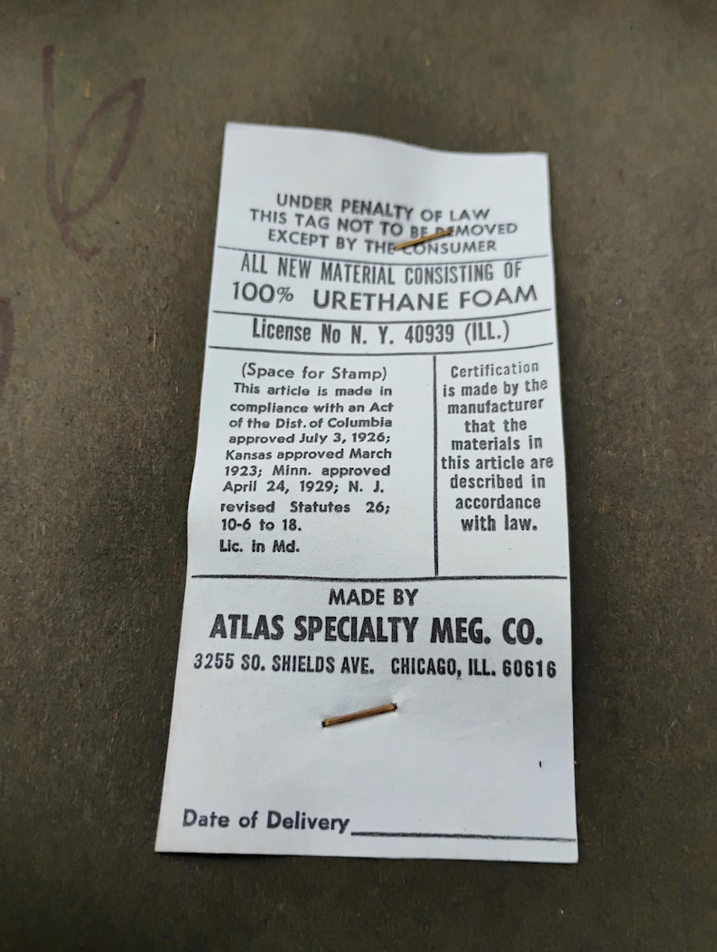 Puede incluir: Una etiqueta de producto rectangular blanca con texto negro que dice: UNDER PENALTY OF LAW THIS TAG NOT TO BE REMOVED EXCEPT BY THE CONSUMER. ALL NEW MATERIAL CONSISTING OF 100% URETHANE FOAM. MADE BY ATLAS SPECIALTY MFG. CO. 3255 SO. SHIELDS AVE. CHICAGO, ILL. 60616.