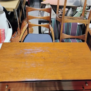 Puede incluir: Una c&oacute;moda de madera con dos cajones y un acabado marr&oacute;n claro. La c&oacute;moda tiene un aspecto ligeramente desgastado con algunos ara&ntilde;azos ligeros en la superficie.