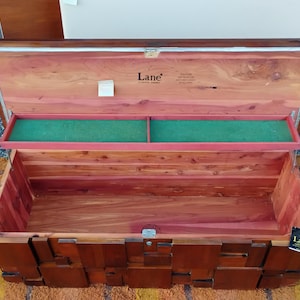 Puede incluir: Arc&oacute;n de cedro de madera abierto, de forma rectangular y con tapa con bisagras. El interior presenta una bandeja verde y madera de tonos rojos. El exterior es de color marr&oacute;n oscuro con un dise&ntilde;o geom&eacute;trico. El arc&oacute;n tiene la marca "Lane".