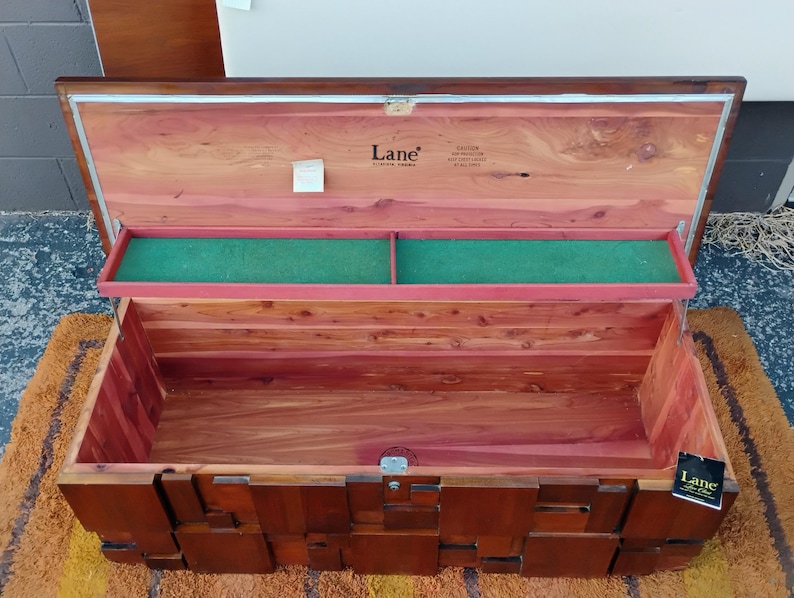 Puede incluir: Arc&oacute;n de cedro de madera abierto, de forma rectangular y con tapa con bisagras. El interior presenta una bandeja verde y madera de tonos rojos. El exterior es de color marr&oacute;n oscuro con un dise&ntilde;o geom&eacute;trico. El arc&oacute;n tiene la marca "Lane".