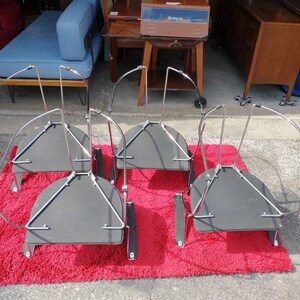 May include: Four black and chrome metal chairs with a curved back and a round seat. The chairs are upside down and are on a red shag rug.