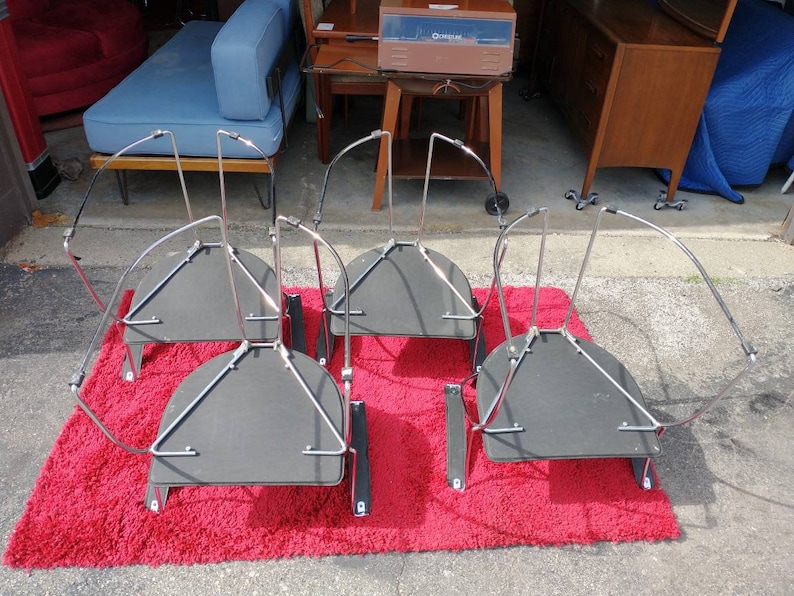 May include: Four black and chrome metal chairs with a curved back and a round seat. The chairs are upside down and are on a red shag rug.