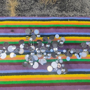 May include: A wall sculpture composed of numerous circular metal discs in varying sizes and finishes, including polished chrome, brushed silver, and matte black, arranged in an expansive, interconnected horizontal cluster with protruding spheres.