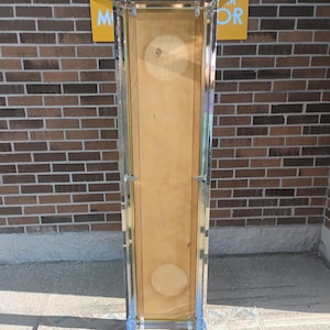 K&ouml;nnte beinhalten: Eine hohe, rechteckige Vitrine mit einer Holzr&uuml;ckwand und einer transparenten Vorderseite. Der Rahmen ist aus silberfarbenem Metall. &Uuml;ber der Vitrine befindet sich ein Schild mit der Aufschrift "MAD 4 MOR" in rosa und wei&szlig;er Schrift auf gelbem Hintergrund. Die Vitrine steht auf einer Betonoberfl&auml;che.