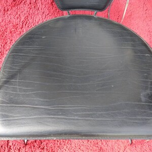 May include: Black leather chair seat with a curved shape and a chrome frame.