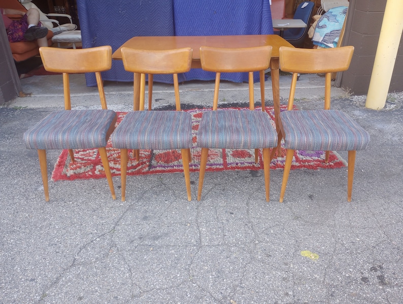 May include: Set of four mid-century modern dining chairs with wooden legs and striped fabric seats.