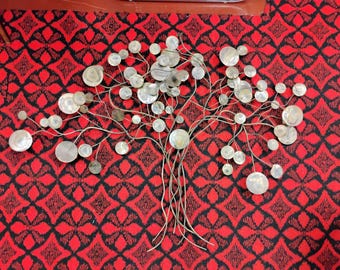 Könnte beinhalten: Metall-Wandkunst in Form eines Baumes mit einem Netzwerk aus dünnen, silberfarbenen Ästen und kreisförmigen, irisierenden Akzenten. Das Kunstwerk befindet sich vor einem rot-schwarz gemusterten Hintergrund.