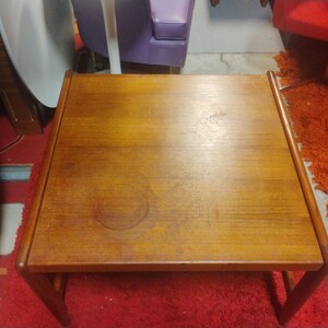 May include: A rectangular wooden coffee table with a light brown finish. The table has a simple design with a flat top and a lower shelf.