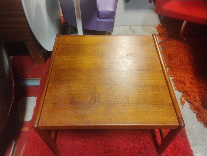 May include: A rectangular wooden coffee table with a light brown finish. The table has a simple design with a flat top and a lower shelf.