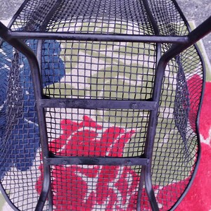 May include: Black metal mesh chair with a curved back and a wide seat. The chair is made of a sturdy metal frame and has a black finish.