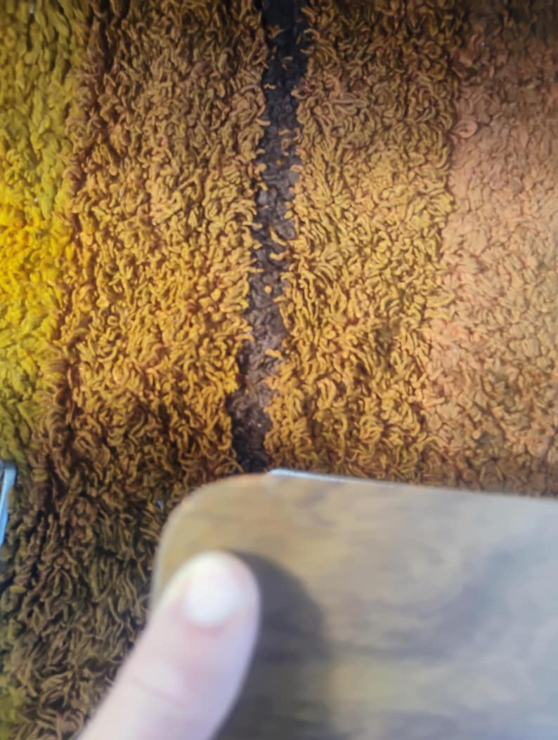 May include: A shaggy rug featuring vertical stripes in shades of yellow, mustard, and dark brown. The texture is dense and looped, creating a thick pile surface. The rug displays a gradient color pattern with distinct color transitions between the stripes.
