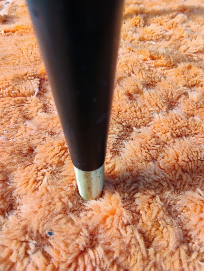May include: A tapered furniture leg with a smooth black finish and a metallic gold-toned ferrule at the base. The leg is cylindrical in shape, narrowing slightly toward the bottom, and features a clean, polished transition between the black and gold.