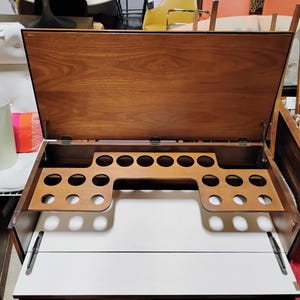 Puede incluir: Un bar de madera con una tapa abatible y un porta botellas incorporado. El bar tiene un acabado de madera clara y est&aacute; abierto, revelando el porta botellas.