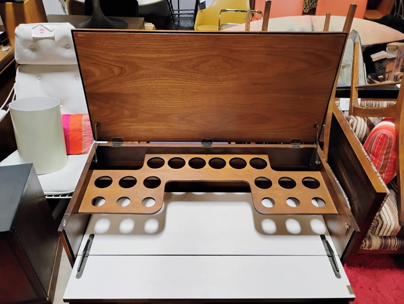 Puede incluir: Un bar de madera con una tapa abatible y un porta botellas incorporado. El bar tiene un acabado de madera clara y est&aacute; abierto, revelando el porta botellas.
