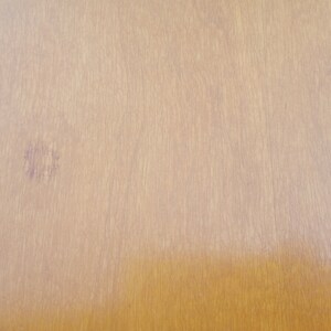 May include: A close-up of a light brown wooden surface with a faint purple stain.