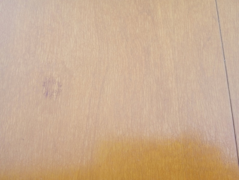 May include: A close-up of a light brown wooden surface with a faint purple stain.