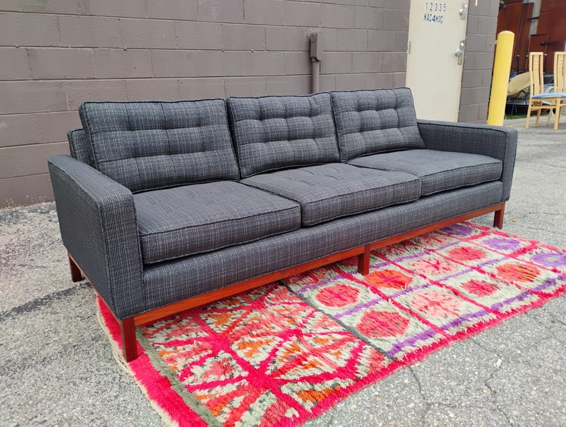 K&ouml;nnte beinhalten: Ein Dreisitzer-Sofa, bezogen mit einem dunkelgrauen, strukturierten Stoff mit einem dezenten Karomuster. Das Sofa verf&uuml;gt &uuml;ber drei getuftete R&uuml;ckenkissen, drei Sitzkissen und einen h&ouml;lzernen Unterbau mit geraden Beinen f&uuml;r eine klare Form.