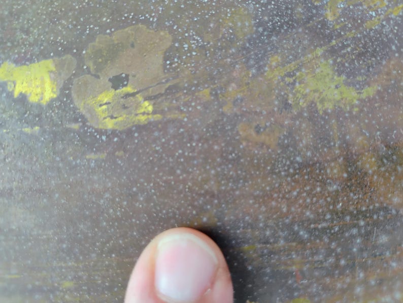 K&ouml;nnte beinhalten: Nahaufnahme einer strukturierten Oberfl&auml;che mit marmoriertem Aussehen. Die Oberfl&auml;che hat eine Mischung aus braunen, gelben und wei&szlig;en Farben mit einem gesprenkelten Muster. Die Textur wirkt rau und gealtert, mit einem Finger im Vordergrund.