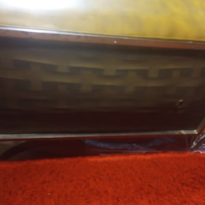 K&ouml;nnte beinhalten: Nahaufnahme der Unterseite eines braunen Ledersofas mit einem Metallrahmen. Das Sofa hat eine gesteppte R&uuml;ckenlehne und ein dekoratives Muster auf der Unterseite.
