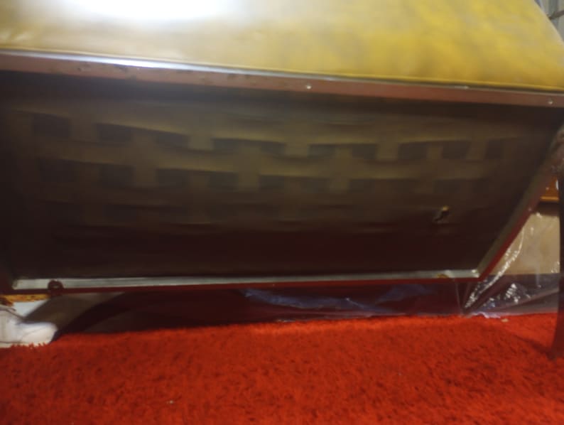 K&ouml;nnte beinhalten: Nahaufnahme der Unterseite eines braunen Ledersofas mit einem Metallrahmen. Das Sofa hat eine gesteppte R&uuml;ckenlehne und ein dekoratives Muster auf der Unterseite.