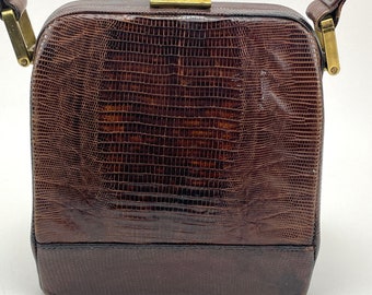 May include: A brown leather handbag with a gold clasp and a short strap. The bag has a textured, snakeskin-like pattern.